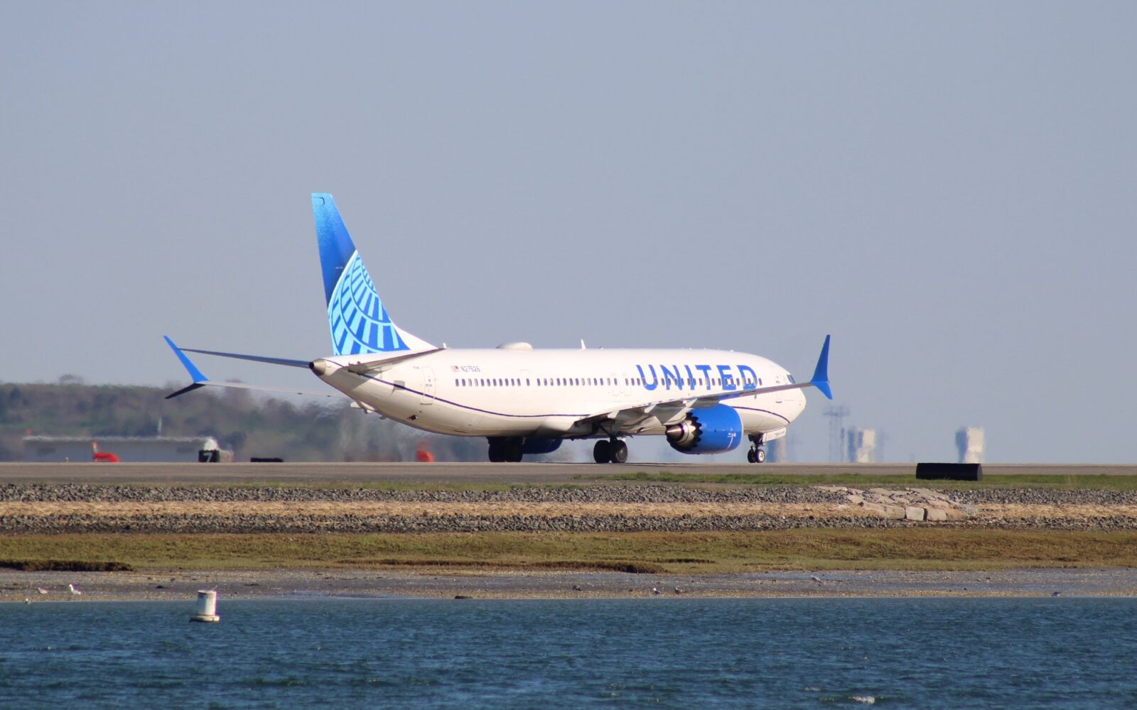 United Airlines aircraft taxiing on a runway beside the water